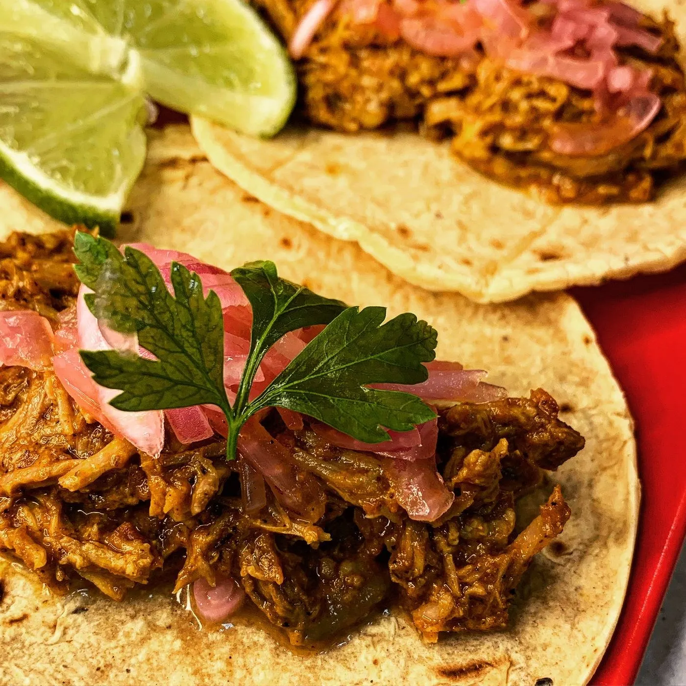 Tacos de cochinita pibil con cebolla morada encurtida y lima