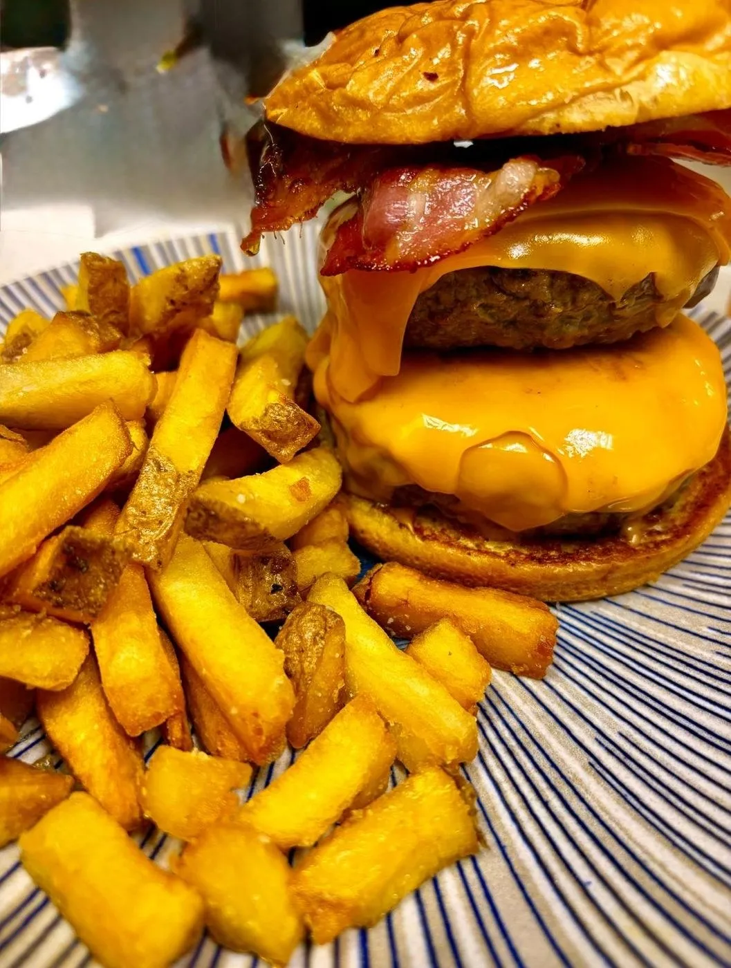 Hamburguesa doble con bacón y queso fundido sobre patatas fritas